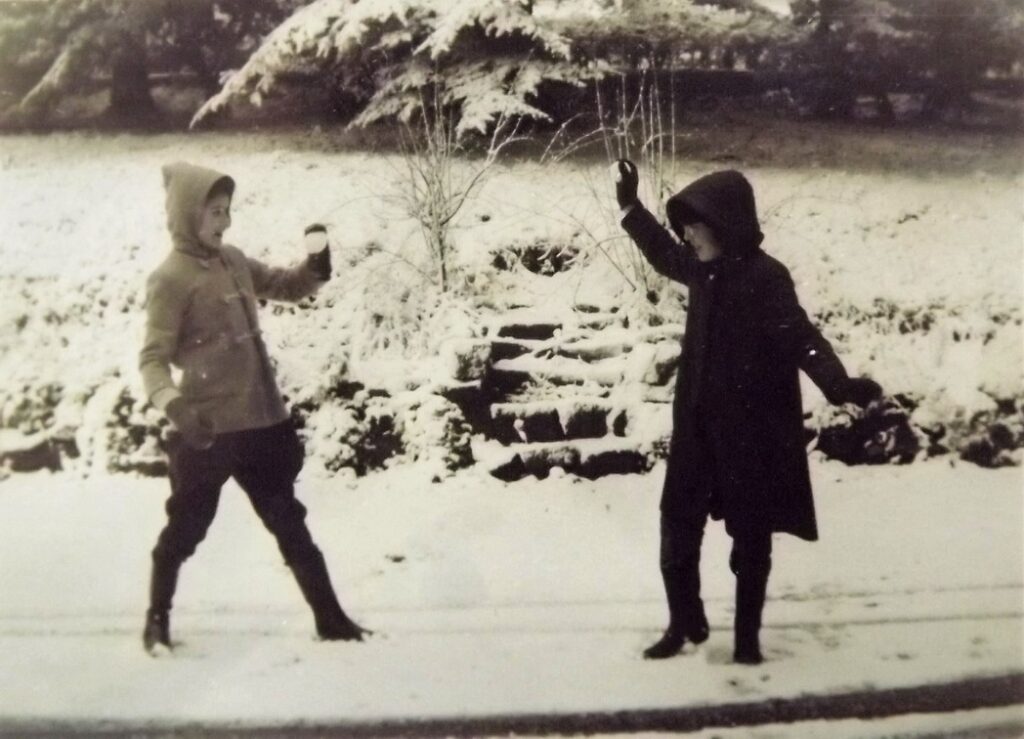 A young boy and girl playing snowball fights